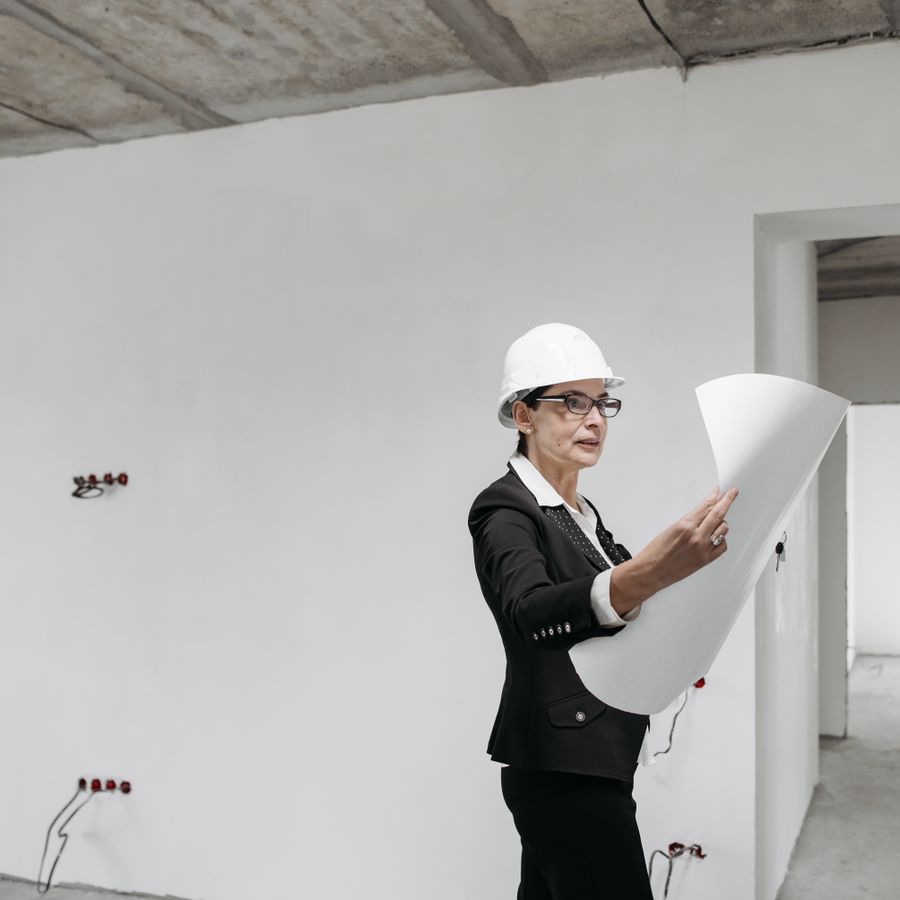 An architect reviewing plans inside a building under construction